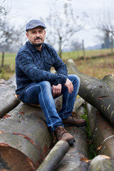 Farmer sitting on a pile of logs