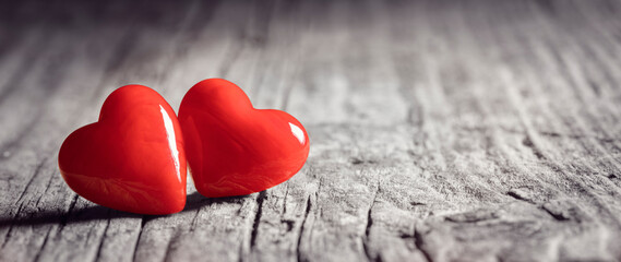 Obraz premium Two red hearts on a wood background concept for love, dating and romance with copy space