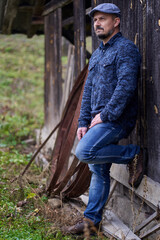 Middle aged man leaning against wooden wall