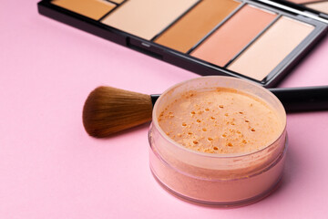 Complexion make up products and brush on pink background