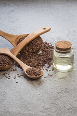 A jar of linseed oil flax seeds in a wooden spoon on a concrete background, a dietary cereal ingredient that reduces cholesterol, a source of omega-3, iodine, phosphorus, potassium, magnesium, nickel
