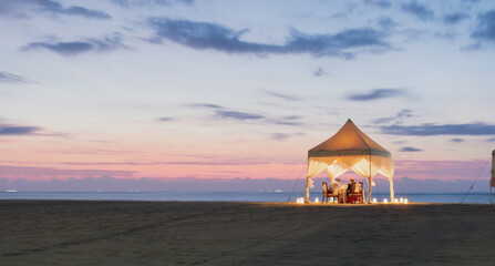 Dinner in the time of sunset at the beach under the canopy. Picture is in long exposure mode to...
