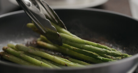 closeup of frozen asparagus cooking on nonstick pan