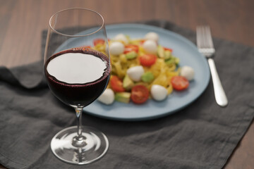 Red wine in thin wine glass with pasta on blue plate