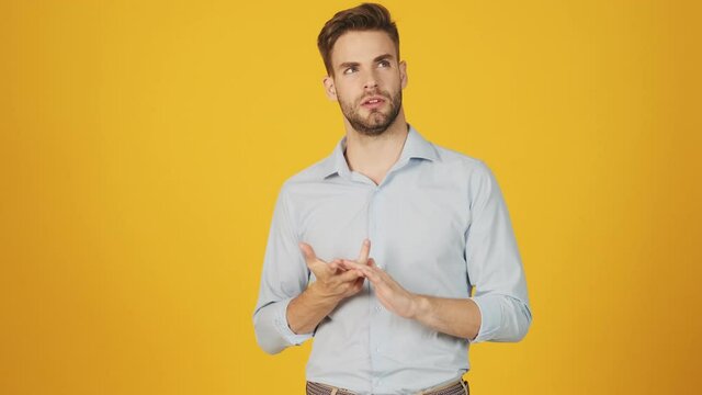 An attractive young man is counting on fingers standing isolated over a yellow background in the studio