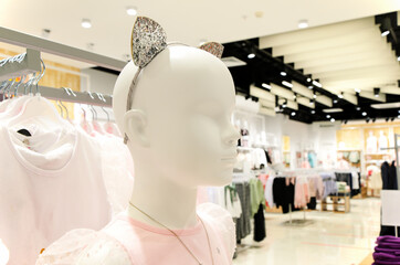 Close-up of head of baby girl mannequin of white plastic, wearing headband with shiny silver ears. Children's clothing store, carnival costume, cosplay. Children's fashion industry.