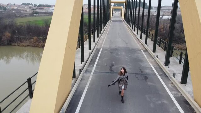 young brunette tourist walking on iron bridge. yellow bridge in foggy day spain 2020