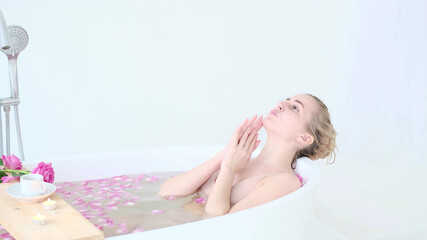 Obraz na płótnie Canvas Beautiful Caucasian Blonde Girl In Bikini Lying In Flower Bath In Resort Day Spa Salon. Skin Care Therapy. Concept young woman relaxing in the bathtube.