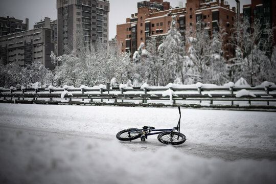 Scenic inusual landscape of a closed highway road for snow with a bycicle in the middle and snowed buildings on the background