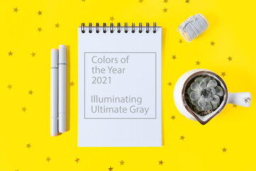 Illuminating Yellow and Ultimate Gray, new colors of the year 2021. Desktop blank notepad . Flat lay of yellow working table background with plants. Top view 