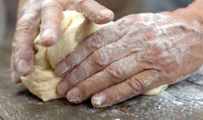 a man kneads dough with his hands on the table