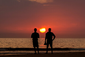 Silueta de dos hombres contemplando el atardecer en la playa de Los Lances, Tarifa, Provincia de Cádiz, Andalucía, España