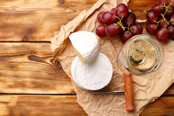Round white cheese with grapes on wooden table