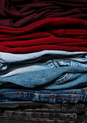 A basic wardrobe, clothes wardrobe. One-on-one folded jeans and blouses in burgundy colors close-up, fall-spring season.