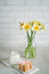 yogurt glass with cookies and yellow flowers in a vase in light background