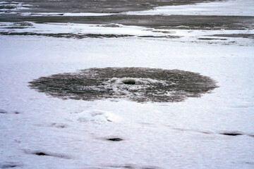 Frozen old fishing hole in the ice on a frozen river. Winter fishing