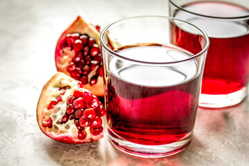 fresh pomegranate with juice in glasses on kitchen background