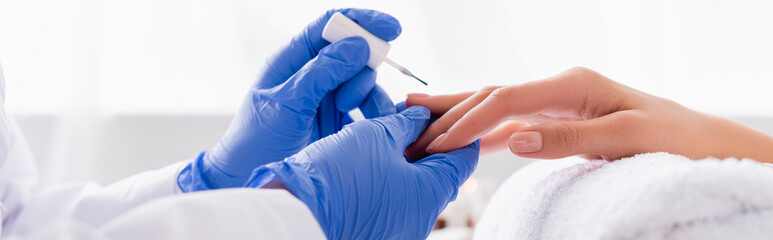 partial view of manicurist applying nail polish on fingernails of client, banner