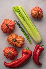 four beautiful ox heart tomatoes ,chives,red pepper  and celery on white background.top view .modern art of photo.