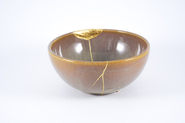Kintsugi brown bowl. Gold cracks restoration on old Japanese ceramic.