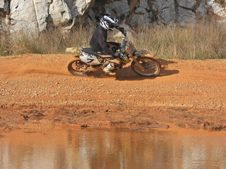 Zoom photo of professional motocross rider on his motorcycle on extreme dirt and mud terrain track....