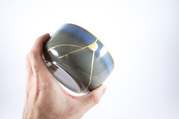 Kintsugi gray pottery. Gold cracks restoration on old Japanese  wabi sabi ceramic.