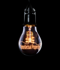 An intellectual Property law concept to protect against creative copyright infringement inside a lit lightbulb on a black background. - obrazy, fototapety, plakaty