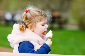 Adorable toddler girl eating sweet ice cream popsicle. food, child, feeding and development concept. Cute happy healthy baby daughter on sunny day outdoors