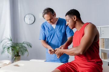 middle aged chiropractor working with african american man in sportswear