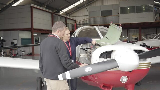 Female flight instructor teaching her student how to do the maintenance of the plane.