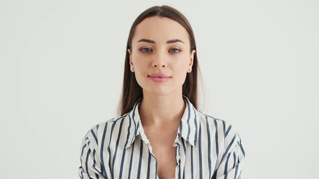 A positive woman is nodding while listening someone standing isolated over white background in studio