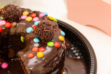 Chocolate cake with brigadeiro topping and colorful chocolate pieces.