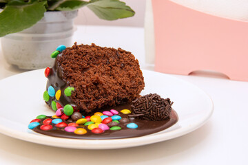 Piece of chocolate cake with brigadeiro topping and colorful chocolate pieces