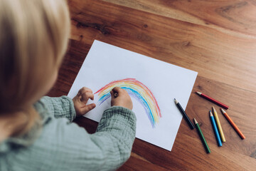 Kleinkind malt bunten Regenbogen mit Buntstiften