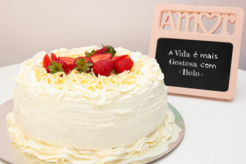 White cake with strawberry icing and pieces of white chocolate. Picture with the word Love at the top and phrase 