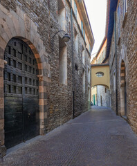view along a medieval, dark and narrow alley with ancient stone houses.Como, Lombardy.Italy