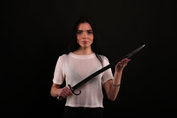 beautiful young brunette woman with a knife on a black background