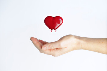 Red love heart melting levitating upon an outstretched female hand against white background. Heartbreak concept.
