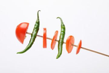 Tomato slices and green chilly in stick on white background