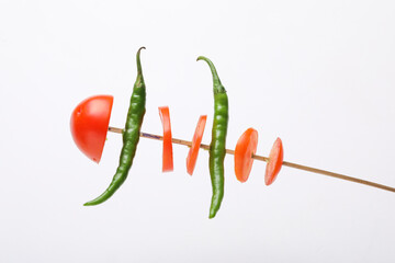 Tomato slices and green chilly in stick on white background