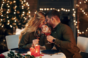 Drinks wine. Young lovely couple have romantic dinner indoors together