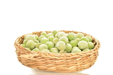 Organic frozen green peas on a straw plate, close-up, isolated on white.