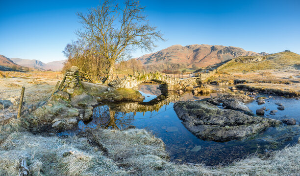 A frosty clear morning with sunshine by old packhorse bridge in the beautiful Lake District
