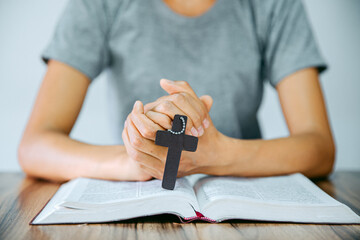 The young lady's hand holding the cross on the bible Make a blessing from God with the power and power of holiness which brings luck and power of religion, faith, worship, Christian thought.