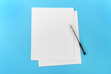 Blank note paper with pen on blue background.