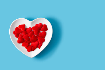 Heart shaped plate with red hearts inside on blue background