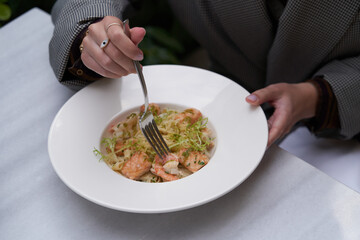 Woman eating Fettuccine pasta with shrimp and cheese.