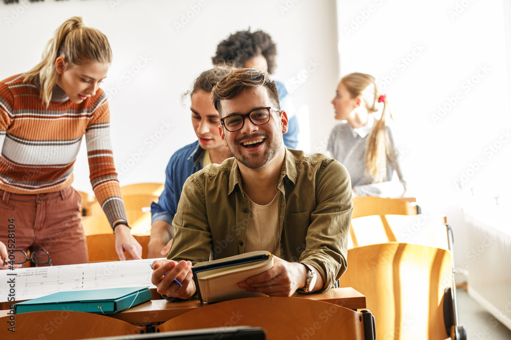 Wall mural portrait of young male university student taking a test in a classroom.educational concept.