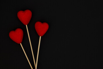 Fototapeta na wymiar Fluffy red hearts, on a wooden stick on black background.