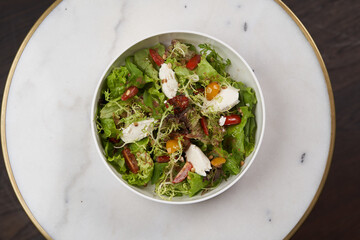 Fresh vegetable salad with feta cheese on a white bowl on table